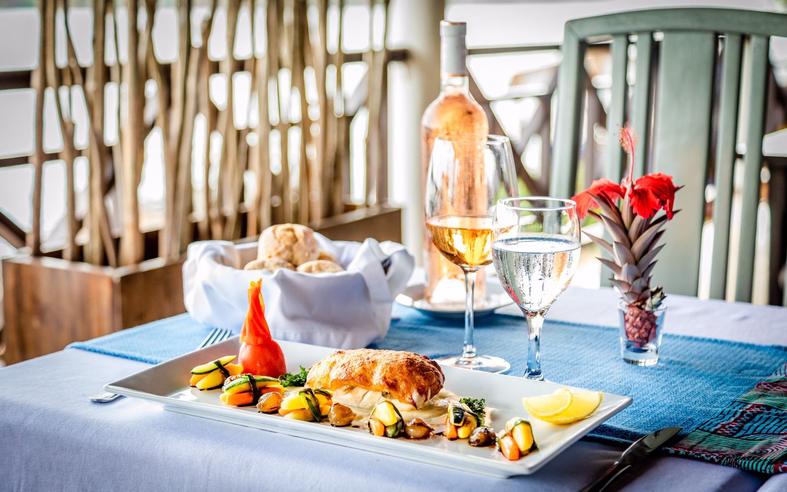 Une table dressée avec un plat, du vin et des fleurs