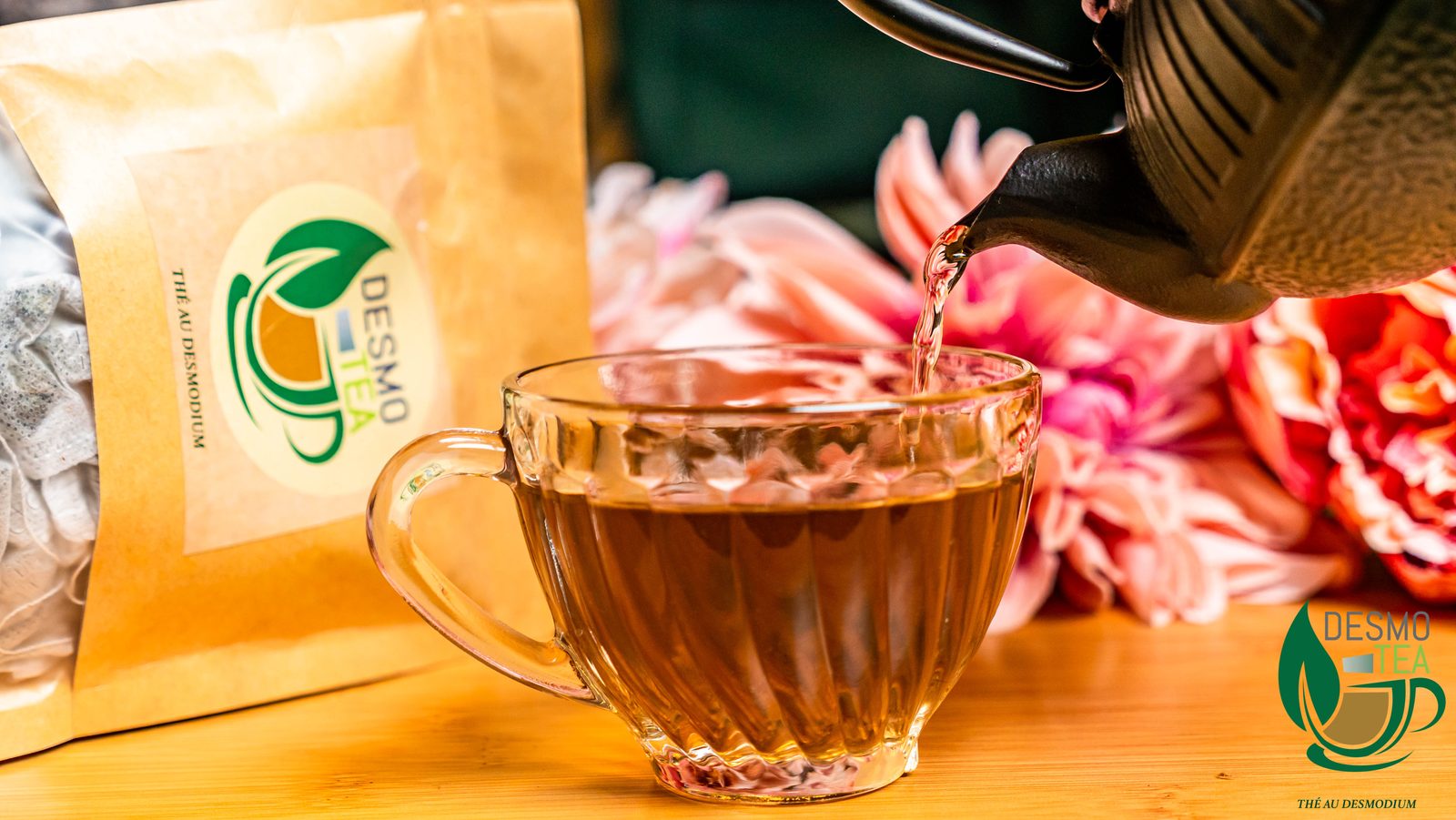 Thé Desmo Tea versé dans une tasse en verre, fleurs en arrière-plan